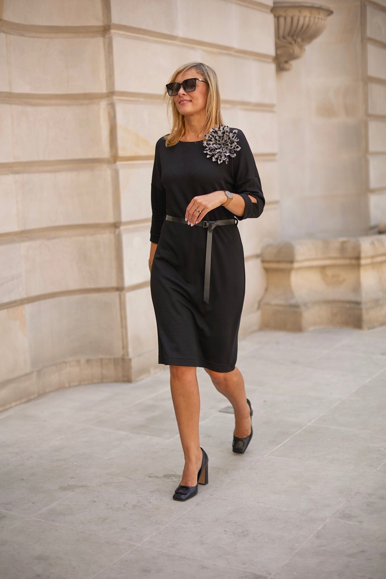 Dzianinowa sukienka w czarny prążek z ozdobnym kwiatem i paskiem